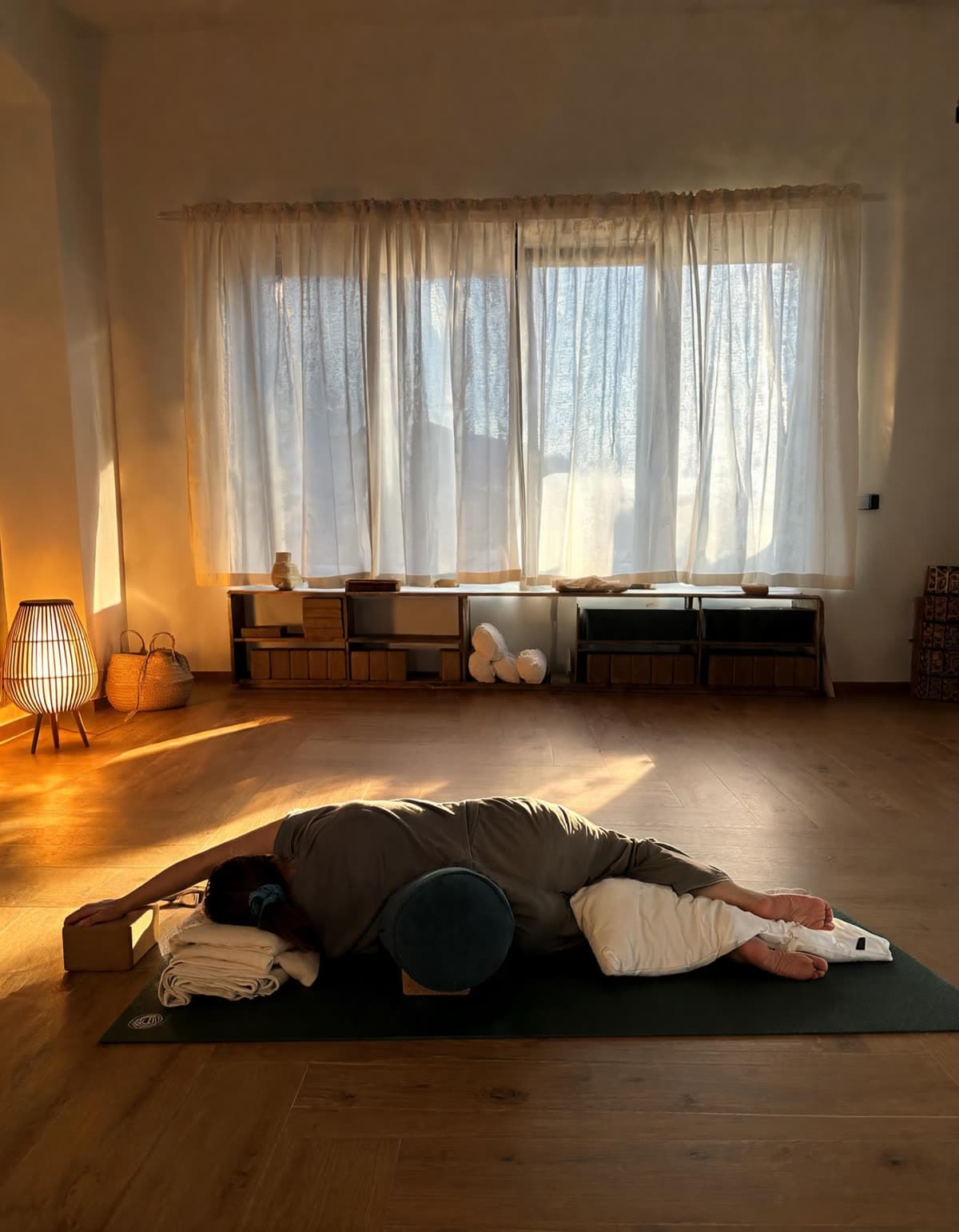 Pratica di riposo con bolster e coperte, nella luce calda della sera